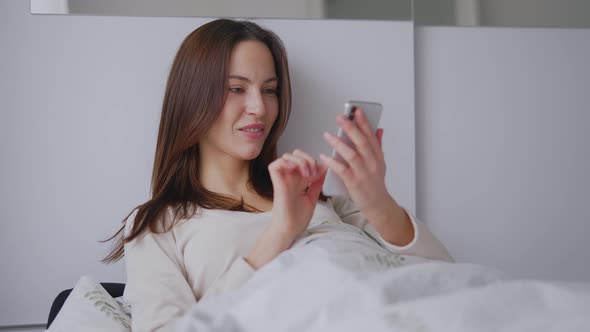Glad Woman Browsing Mobile Phone on Bed