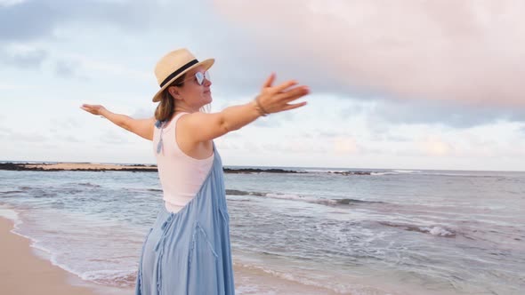 Smiling Woman on Ocean Beach at Cinematic Sunrise Pink Clouds Above Calm Ocean