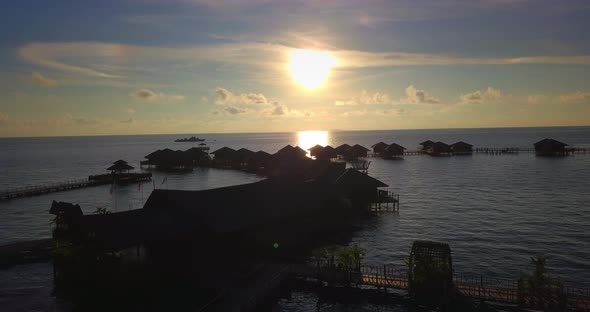 Aerial flight towards stunning sunset over floating huts in Mabul, Malaysia