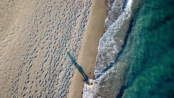 Aerial Drone Footage of a Girl Walking Along a Lonely Beach