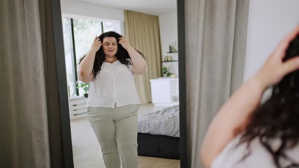 Young Plussize Woman Looks at Mirror Reflection Smiling