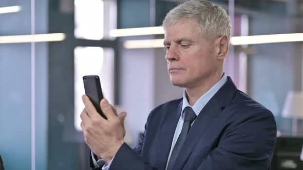 Portrait of Shocked Middle Aged Businessman Using Cellphone