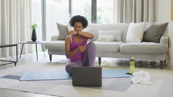 Happy african american wearing sportswear, exercising, using laptop