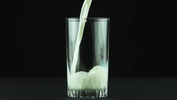 Milk Pouring Into Glass Close Up Isolated on Black Background Slow Motion