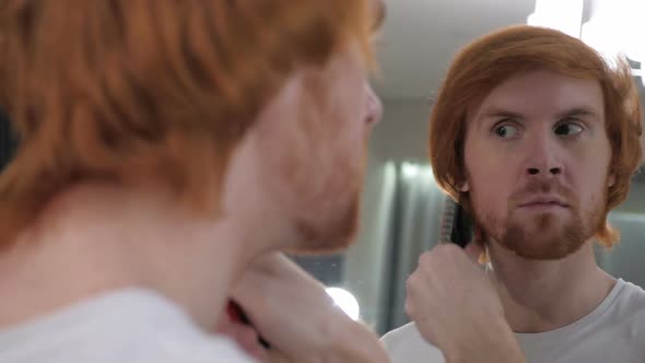 Redhead Beard Man Combing Hairs in Mirror