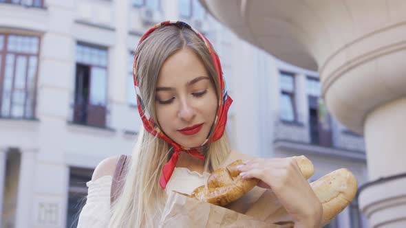 Portrait of Beautiful Young Woman Standing on the Street Holding Freshly Baked Bread and Croissant