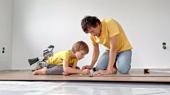 Father and His Little Son Install Laminate on the Floor in Their Apartment