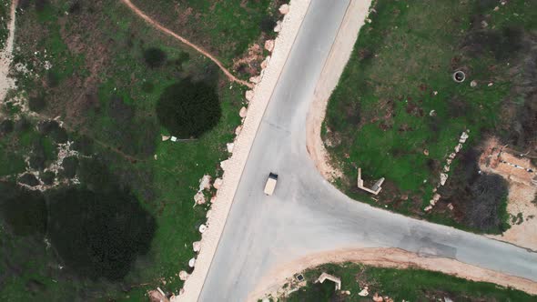 Aerial drone shot of a golf car driving on a road