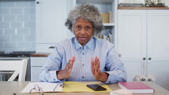 Portrait of senior african american female doctor wearing earphones talking while having a videocall