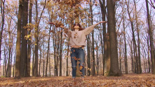 Girl Tossing Colorful Autumn Foliage Up in Air in Park.