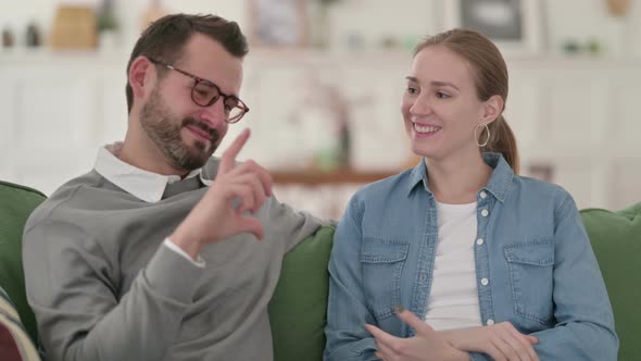 Attractive Couple Having Conversation While Sitting on Sofa