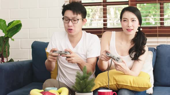 asian family husband and wife enjoy quality time with game console tv monitor challenge together