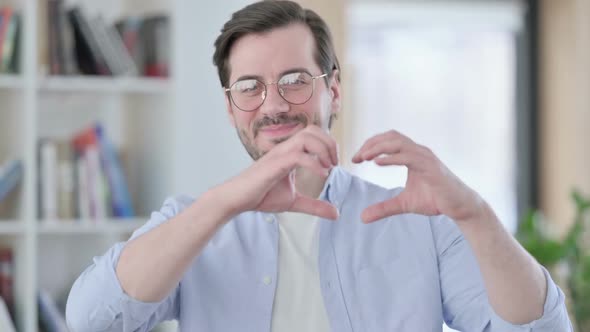 Portrait of Man in Glasses Showing Heart Sign By Hand