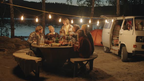 Young Friends Clinking Drinks in Toast at Camping Dinner