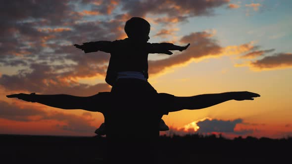 Happy Family Father and Little Son Silhouettes Playing on Meadow