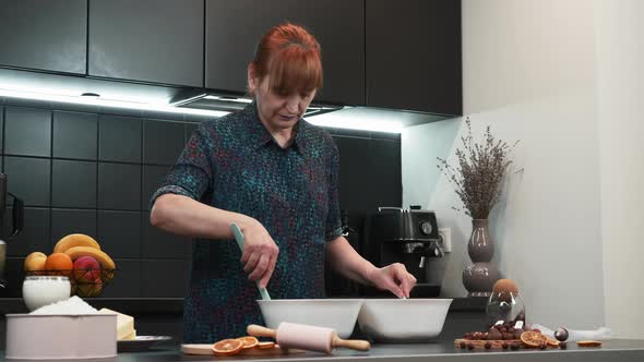 Woman is mixing dough with pastry spatula. 