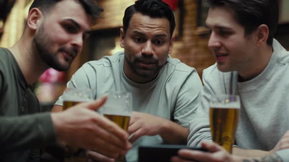 Three male friends watching football match on phone in the pub. Shot with RED helium camera in 8K.