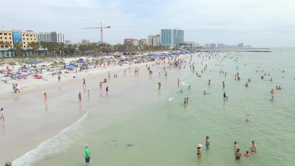 People enjoying a beautiful white sand beach in Clearwater Florida, aerial view