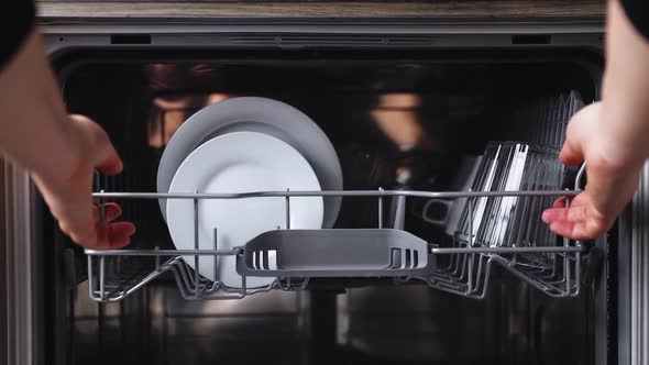Female Hands Extract Basket of Dishwasher Takes Washed Plate From Open Machine