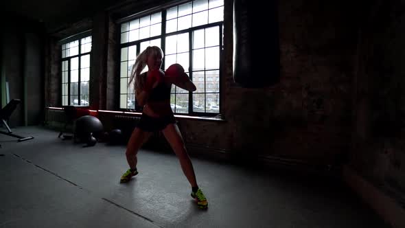 Female Boxer Is Training Alone in Gym, Punching Bag By Hands in Gloves, Sport Activity