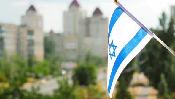 National Flag of Israel set against blue sky and city street. Israeli flag a blue hexagram, stripes