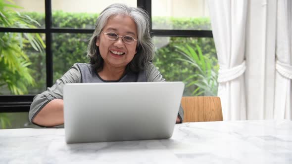 Asian elderly woman is communicating with another person, through online channels