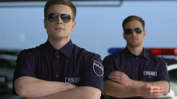 Experienced Policemen in Sunglasses Crossing Hands and Looking Into Camera