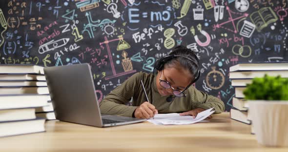 Girl kid studying and writing with headset
