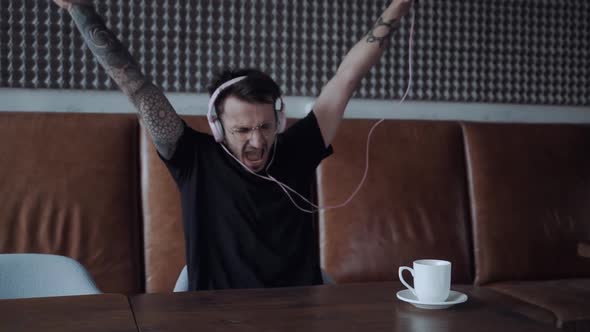 Handsome Young Man in Headphones Listening to Music Immitating Piano Player