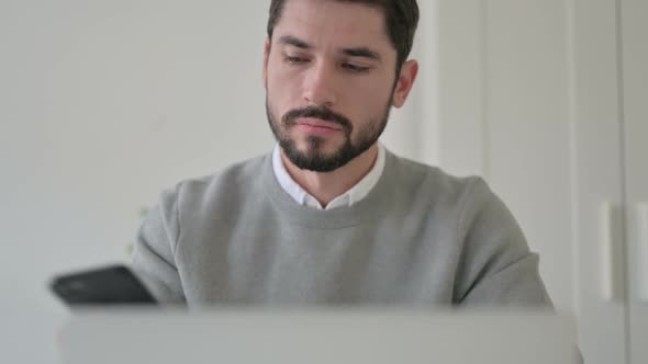 Close Up of Man Talking on Smartphone While Using Laptop
