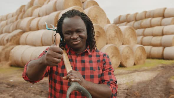 Portrait of Young African Farmer with Pitchfork Over His Shoulder, Thumb Up