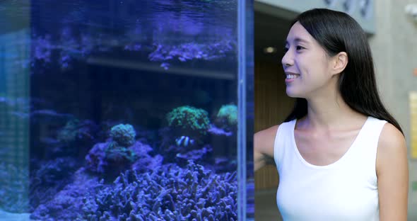 Woman in the aquarium watching the fish 