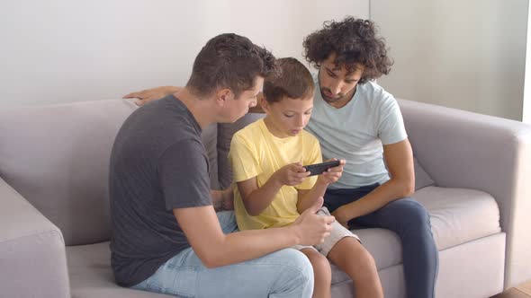 Two Dads Helping Son with Online App on Mobile Phone