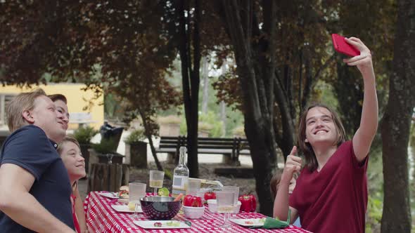 Back View of Family Sitting at Table and Taking Selfie at Picnic