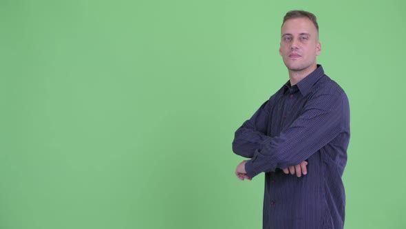 Profile View of Happy Handsome Businessman Smiling with Arms Crossed