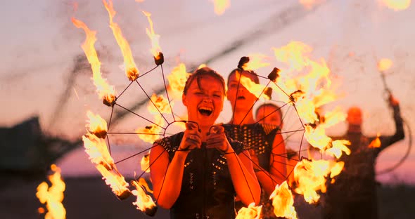 Women with Fire at Sunset on the Sand Dance and Show Tricks Against the Beautiful Sky in Slow Motion