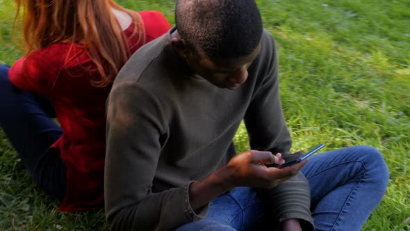 Youth,technology,devices.Mixed lfriends using smartphones sitting on the grass