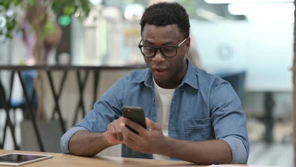 Successful Young African Man Celebrating on Smartphone