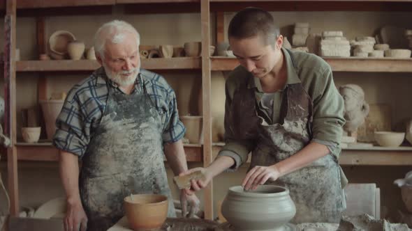 Young Woman Learning Wheel Throwing with Elderly Potter