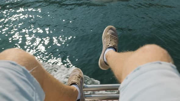 Men's legs and splashes from waves on a ship at sea