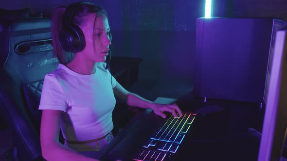 Young Concentrated Gamer Woman Playing Using PC in the Gaming Club
