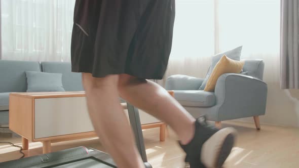 Back View Of Asian Man Running On A Treadmill At Home