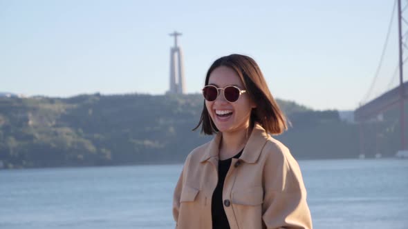 Happy and smiling Thai tourist in front of landmark statue Cristo Rei in Lisbon