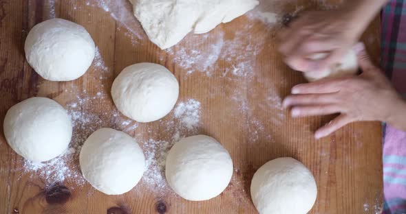 Baker hands kneading dough in flour on the table