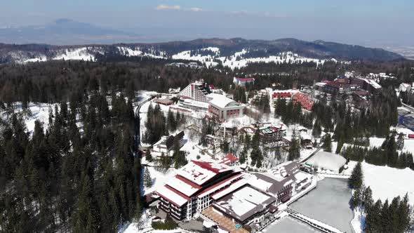 Panoramic aerial view of a frozen pond and famous hotels in Poiana Brasov ski resort