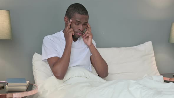 Young African Man with Headache Sitting in Bed 