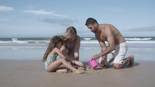 Parents and Cute Little Girl Playing with Toy Shovel