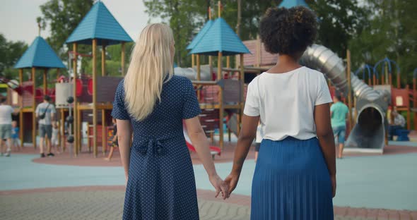 Rear View of Diverse Lesbian Couple Holding Hands Standing on Outdoors Playground
