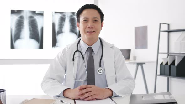 young Asia male doctor with stethoscope looking at camera and smiling while video conference call.