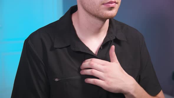 A Young Caucasian Male in a Medical Uniform Does a Selfmassage of His Chest Muscles with His Fingers